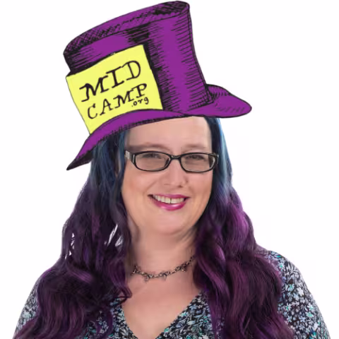 Smiling person with purple and blue hair wearing glasses and a whimsical purple top hat labeled “MidCamp.”